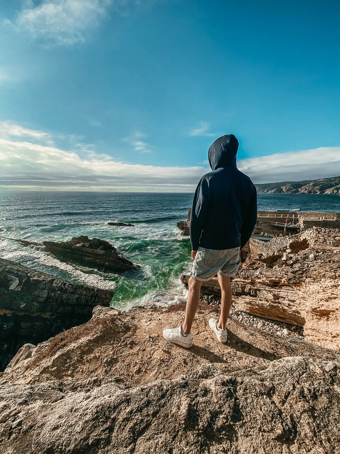 Roman standing on rocks above the sea